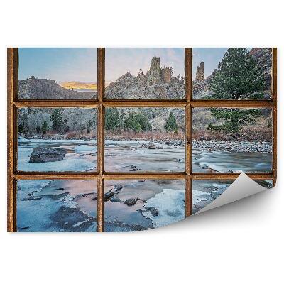 Samolepící fototapeta Staré okno s výhledem na hory a zamrzlý potok